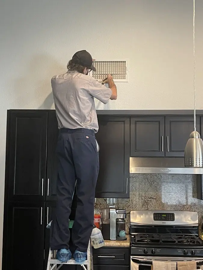 Technician inspecting an air vent during HVAC service in Southborough